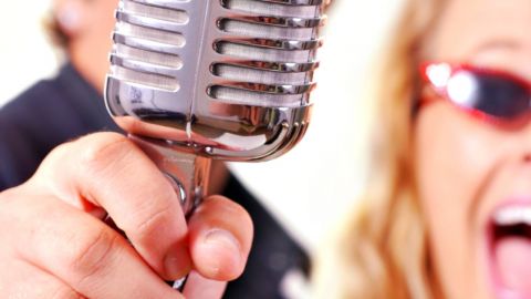 Image of man and woman singing into a microphone.