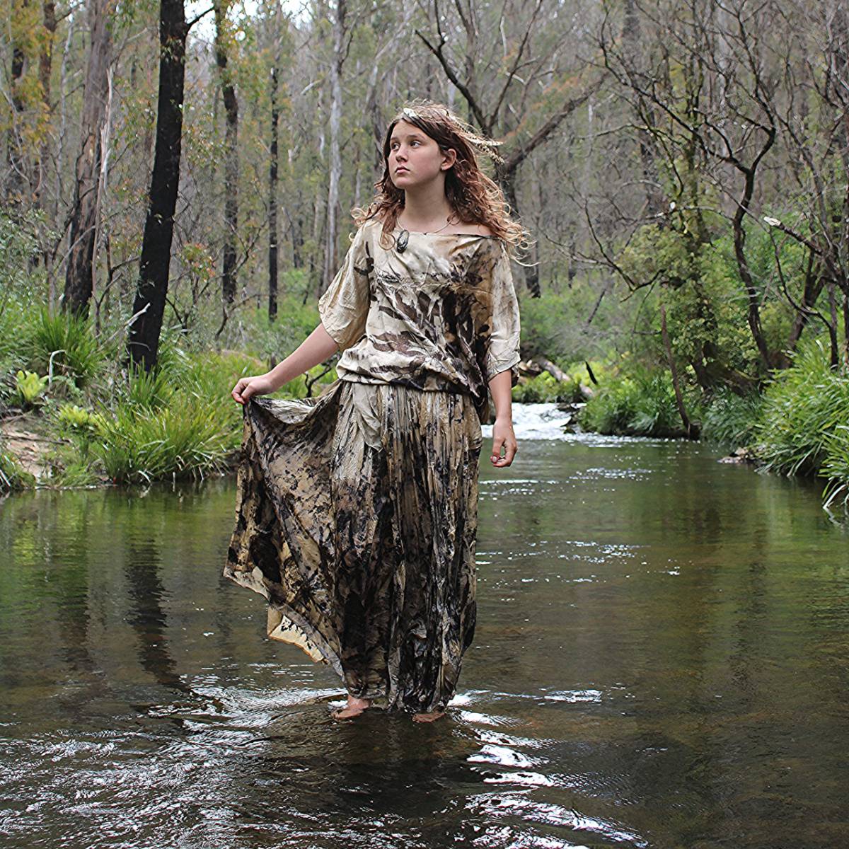 Image Image of girl dressed in botanical print and standing in a shallow creek.