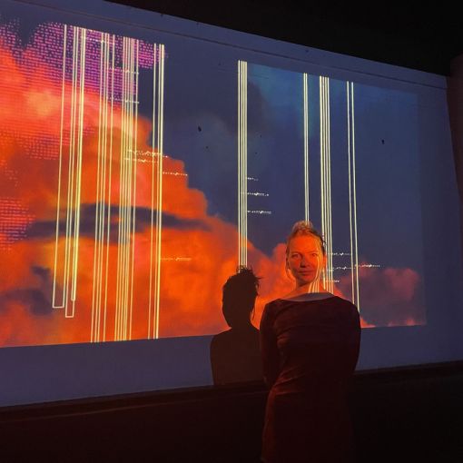A young woman standing in front of a digital projection.